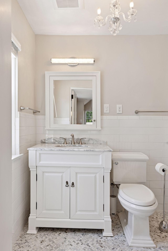 4201 Dupont Ave S, Minneapolis, MN 55409 - bathroom with tile walls, vanity, toilet, a chandelier, and wainscoting