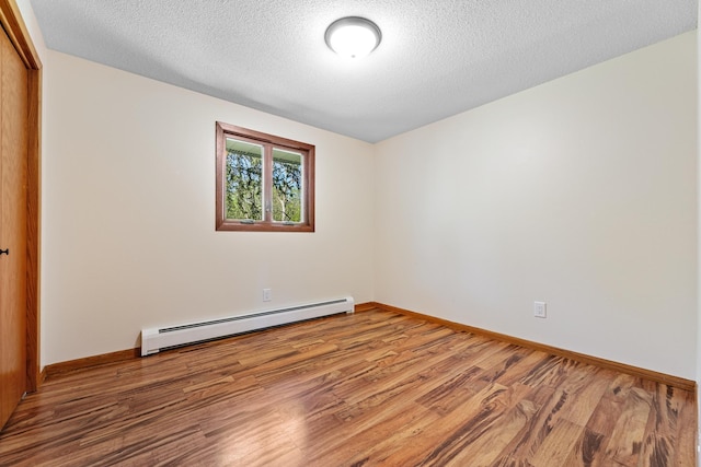 unfurnished bedroom with a baseboard radiator, a closet, wood finished floors, baseboards, and a textured ceiling