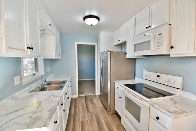 kitchen featuring white appliances, a sink, light wood finished floors, white cabinets, and light stone countertops
