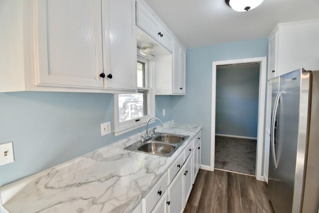 kitchen with freestanding refrigerator, a sink, white cabinets, dark wood-type flooring, and light stone counters