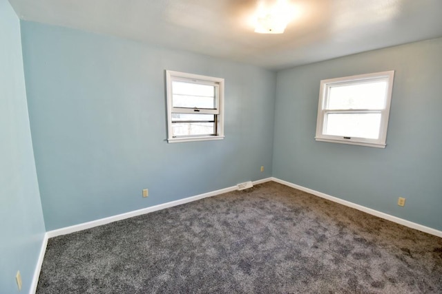 unfurnished room with healthy amount of natural light, carpet, and baseboards