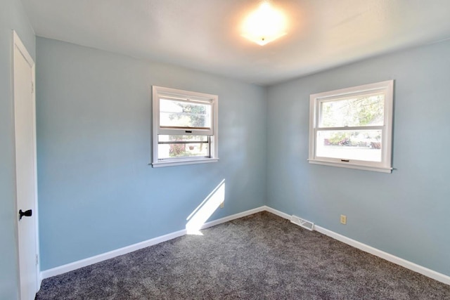 unfurnished room with dark colored carpet and baseboards