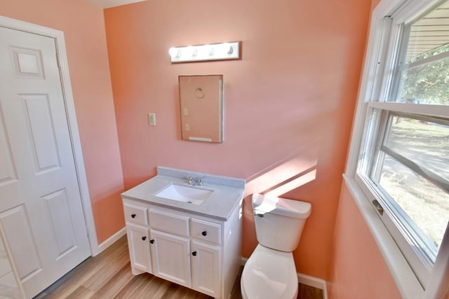 bathroom featuring wood finished floors, toilet, vanity, and baseboards
