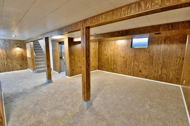 below grade area featuring wooden walls, carpet floors, and stairway