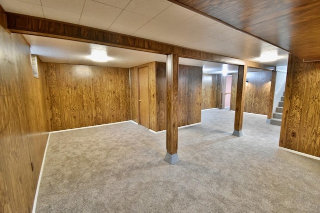 finished basement featuring wood walls, carpet floors, and stairs