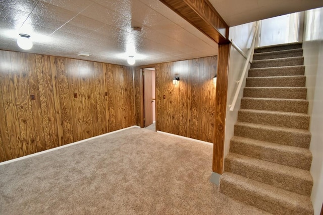 finished below grade area featuring stairs, wooden walls, and carpet flooring