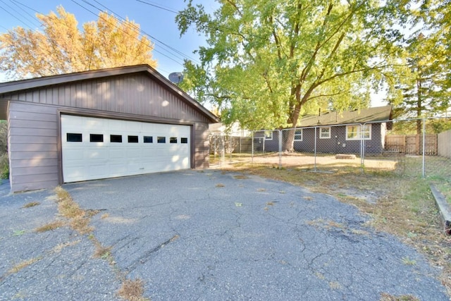 view of side of property featuring fence, a detached garage, and an outbuilding