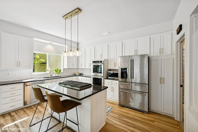 820 Vineland Ct, Chanhassen, MN 55317 - kitchen with stainless steel appliances, a sink, a breakfast bar, white cabinets, and light wood finished floors