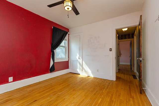 spare room featuring hardwood / wood-style flooring, a ceiling fan, and baseboards