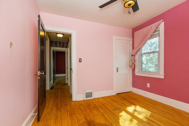 unfurnished bedroom featuring light wood-type flooring, baseboards, and a ceiling fan