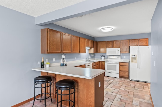 7954 Timber Lake Dr, Eden Prairie, MN 55347 - kitchen with white appliances, a peninsula, light countertops, brown cabinets, and a kitchen bar