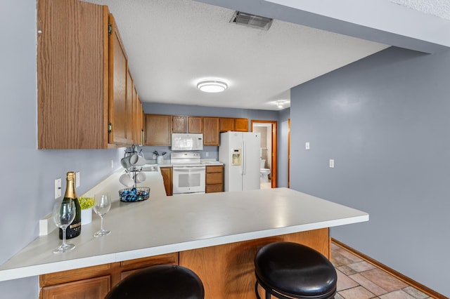 7954 Timber Lake Dr, Eden Prairie, MN 55347 - kitchen featuring white appliances, a peninsula, light countertops, brown cabinets, and a kitchen breakfast bar