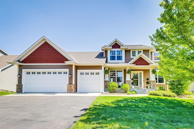 craftsman house featuring stone siding, an attached garage, asphalt driveway, a front lawn, and a porch