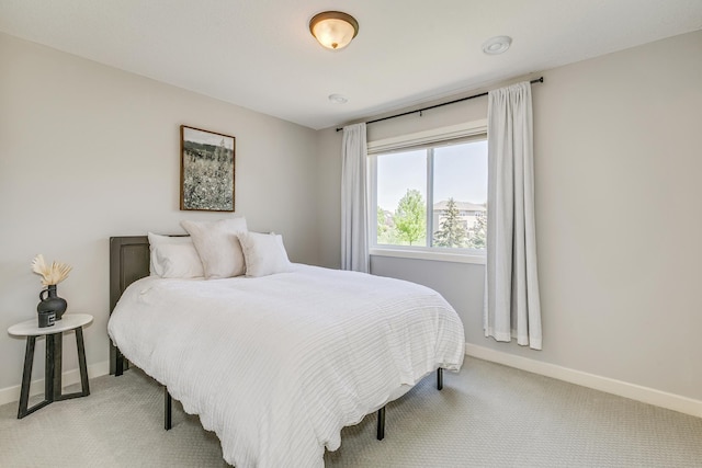 bedroom with light colored carpet and baseboards