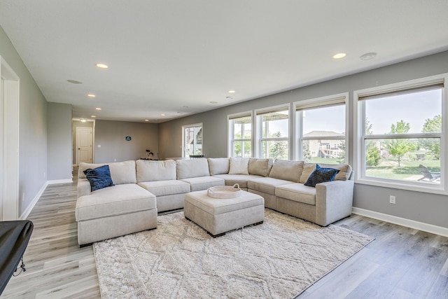 living room featuring healthy amount of natural light, recessed lighting, light wood-style flooring, and baseboards
