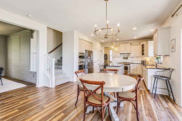 dining room with wood finished floors, a chandelier, recessed lighting, and stairs