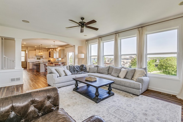 living room with wood finished floors, ceiling fan, arched walkways, baseboards, and recessed lighting