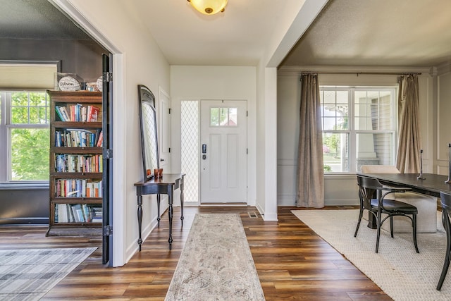 foyer with dark wood-style flooring and baseboards