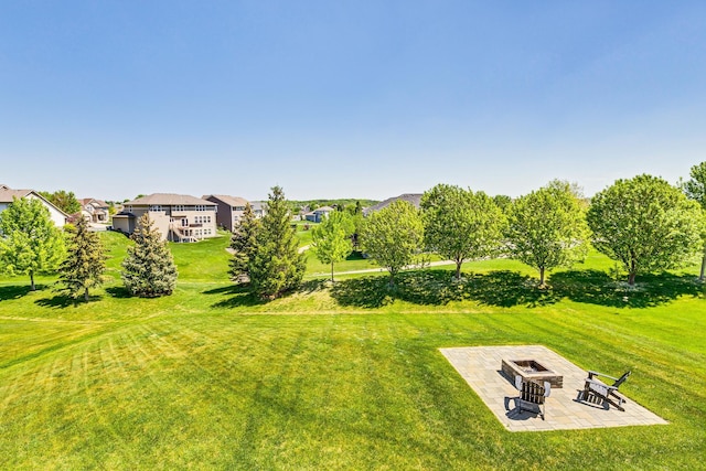 view of grassy yard with a patio and an outdoor fire pit