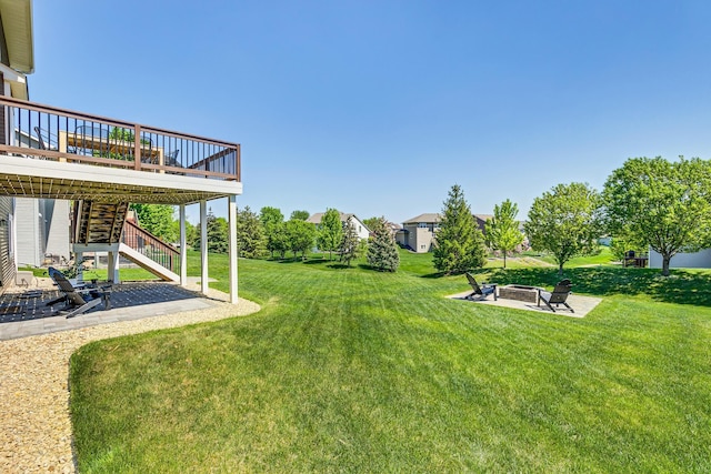 view of green lawn featuring an outdoor fire pit, stairway, a wooden deck, and a patio area