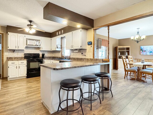 2216 County Road 15, Russell, MN 56169 - kitchen featuring black / electric stove, white microwave, a peninsula, a sink, and dark countertops