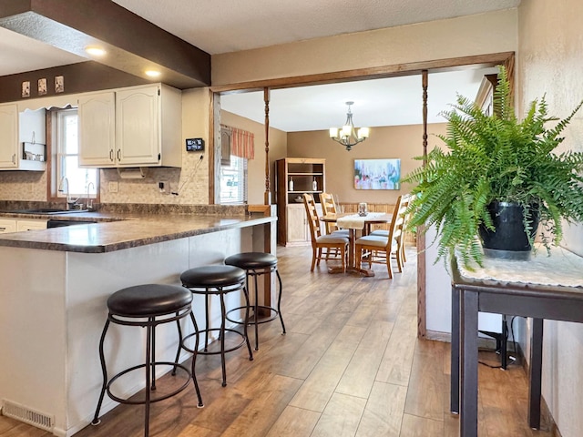 2216 County Road 15, Russell, MN 56169 - kitchen with dark countertops, white cabinets, backsplash, and a breakfast bar