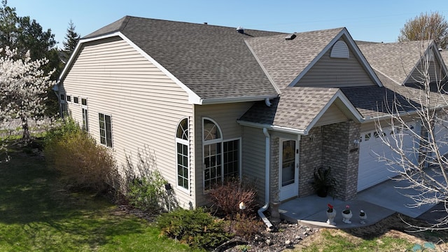 view of property exterior with roof with shingles and an attached garage