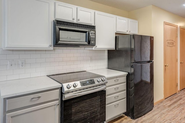 kitchen featuring black appliances, light wood finished floors, light countertops, and decorative backsplash