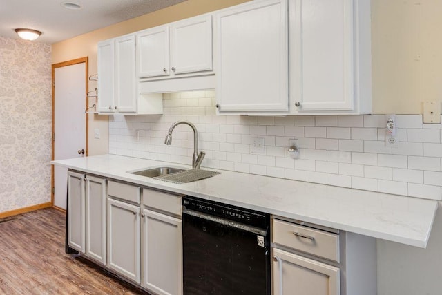 kitchen featuring dishwasher, a sink, wallpapered walls, wood finished floors, and decorative backsplash