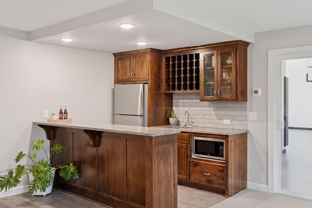 62 Rapp Farm Blvd, North Oaks, MN 55127 - kitchen featuring freestanding refrigerator, stainless steel microwave, light stone counters, glass insert cabinets, and a sink