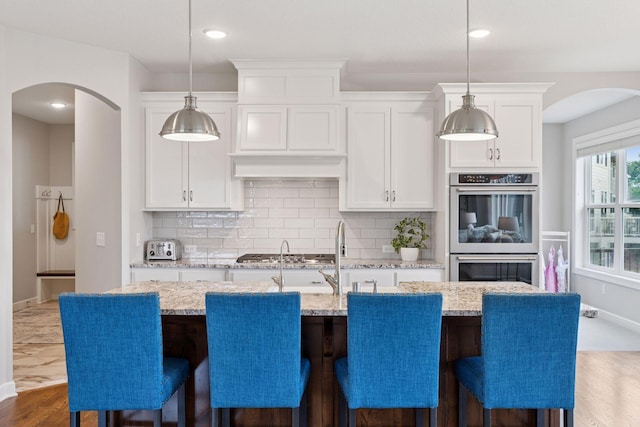 62 Rapp Farm Blvd, North Oaks, MN 55127 - kitchen featuring arched walkways, appliances with stainless steel finishes, dark wood finished floors, tasteful backsplash, and recessed lighting
