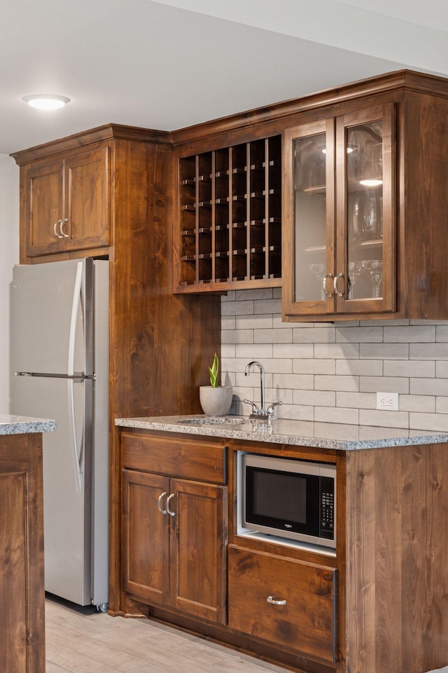 62 Rapp Farm Blvd, North Oaks, MN 55127 - kitchen with freestanding refrigerator, decorative backsplash, glass insert cabinets, light stone countertops, and a sink