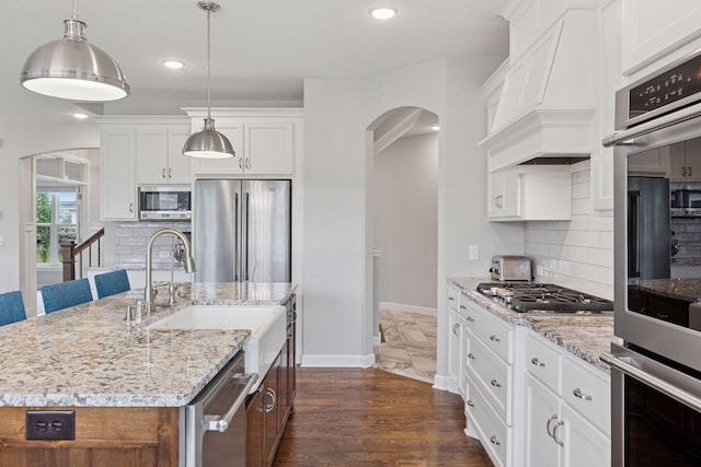 62 Rapp Farm Blvd, North Oaks, MN 55127 - kitchen featuring appliances with stainless steel finishes, arched walkways, white cabinetry, custom exhaust hood, and recessed lighting