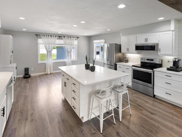 10308 Belmont Rd, Minnetonka, MN 55305 - kitchen featuring appliances with stainless steel finishes, recessed lighting, white cabinets, dark wood-type flooring, and a center island