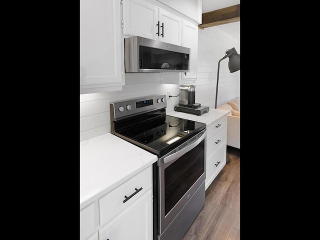 10308 Belmont Rd, Minnetonka, MN 55305 - kitchen featuring appliances with stainless steel finishes, white cabinetry, wood finished floors, and light stone counters