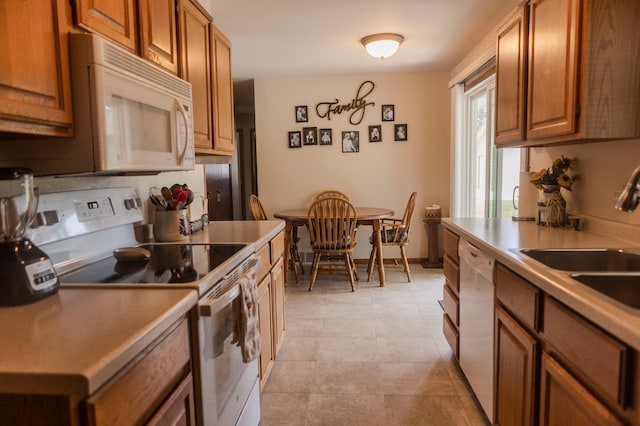 kitchen with white appliances, brown cabinets, and a sink