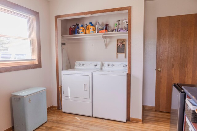 clothes washing area featuring separate washer and dryer, light wood finished floors, and baseboards