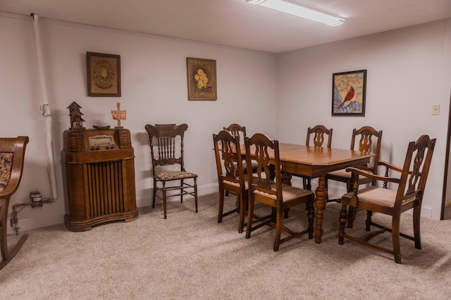 carpeted dining space with ornamental molding and baseboards