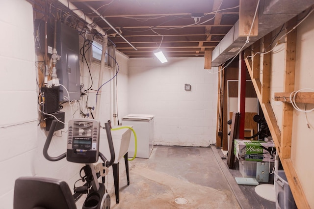 unfinished basement with fridge and concrete block wall