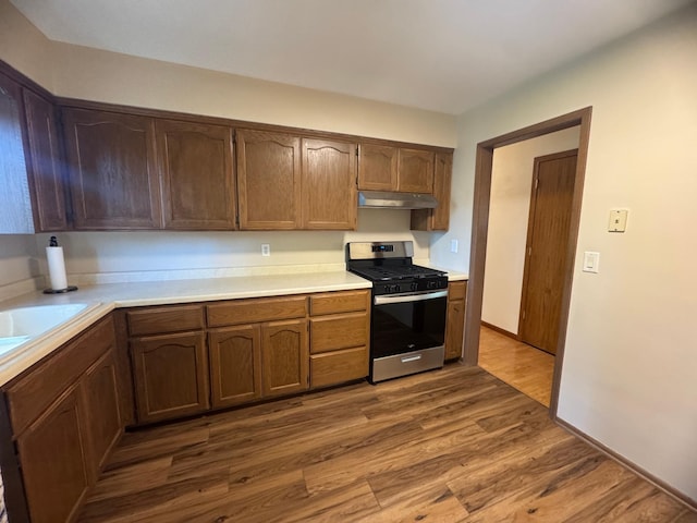 1601 8th Ave NE, Owatonna, MN 55060 - kitchen featuring stainless steel gas range, under cabinet range hood, light countertops, and dark wood-style floors
