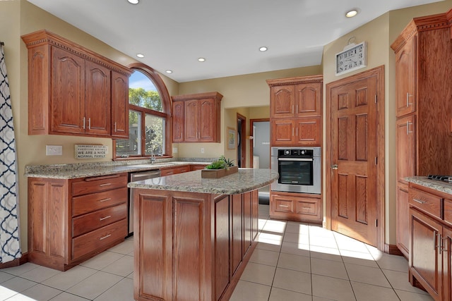 kitchen featuring stainless steel appliances, a sink, a kitchen island, light stone counters, and recessed lighting
