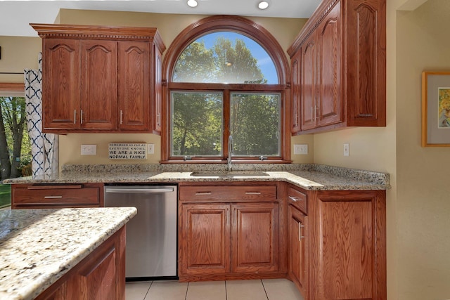 kitchen with stainless steel dishwasher, a sink, light stone counters, brown cabinetry, and recessed lighting
