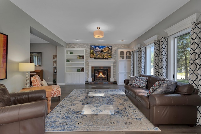living area with dark wood-style flooring, a large fireplace, and built in features