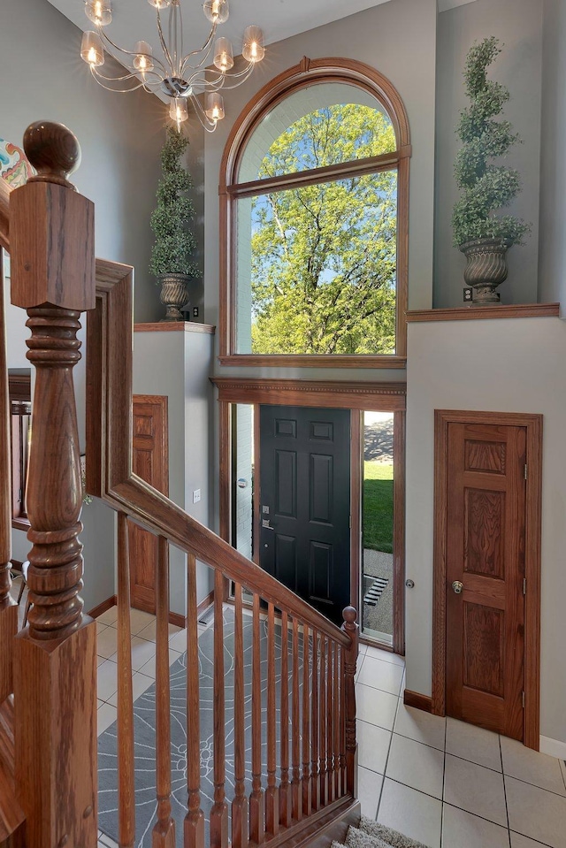 foyer entrance featuring tile patterned flooring, a chandelier, and baseboards