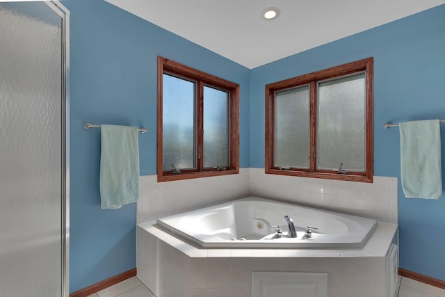 bathroom with baseboards, a tub with jets, and tile patterned flooring