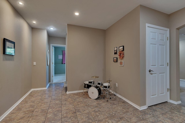 corridor with baseboards, recessed lighting, and stone finish flooring