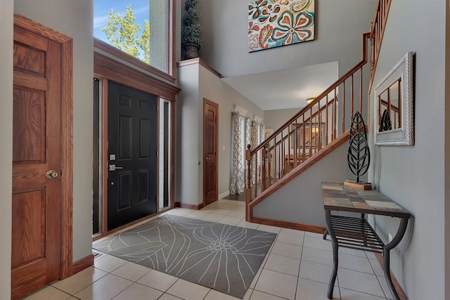 entrance foyer featuring stairway, tile patterned floors, a high ceiling, and baseboards