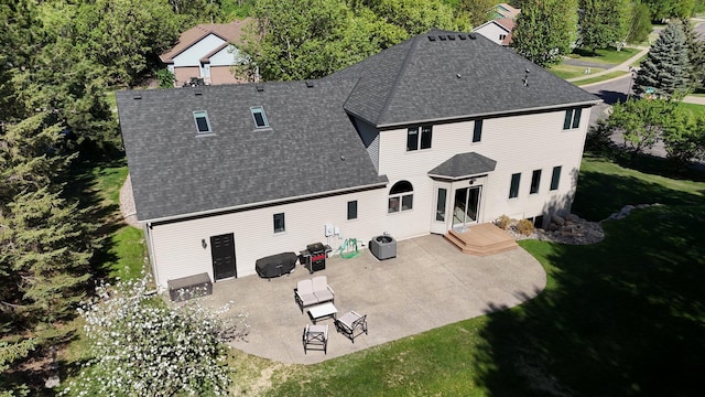 rear view of house with a shingled roof, a patio area, a yard, and cooling unit