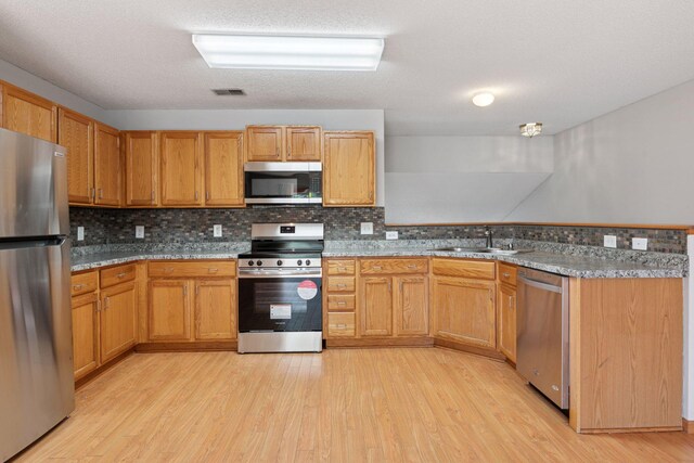 1515 Yorkshire Ln, Shakopee, MN 55379 - kitchen with stainless steel appliances, a sink, light wood-type flooring, a peninsula, and tasteful backsplash