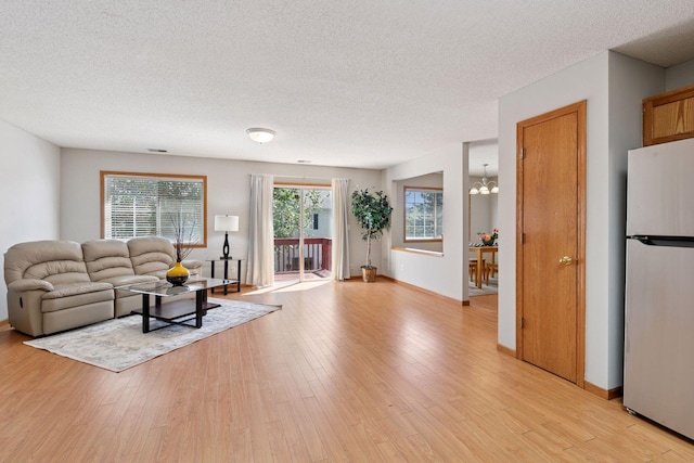 1515 Yorkshire Ln, Shakopee, MN 55379 - living room with a textured ceiling, light wood-style flooring, a chandelier, and baseboards